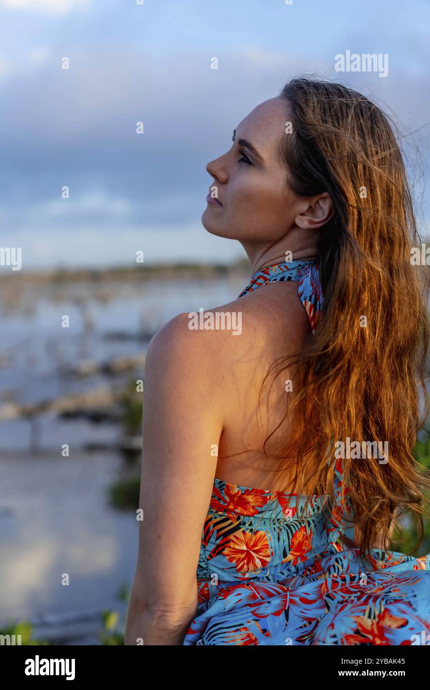 In den pulsierenden mexikanischen Tropen posiert eine atemberaubende Frau im üppigen Grün, während die Sonne Yucatan untergeht und ihr goldenes Licht auf die Natur wirft Stockfoto