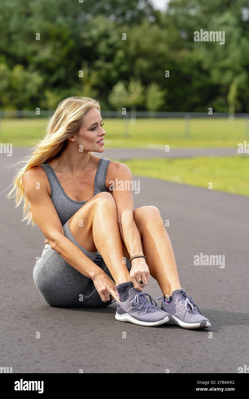 Ein atemberaubendes, blondes Fitnessmodell bereitet sich auf ein Workout vor, das Selbstvertrauen und Entschlossenheit bei jeder Bewegung ausstrahlt Stockfoto