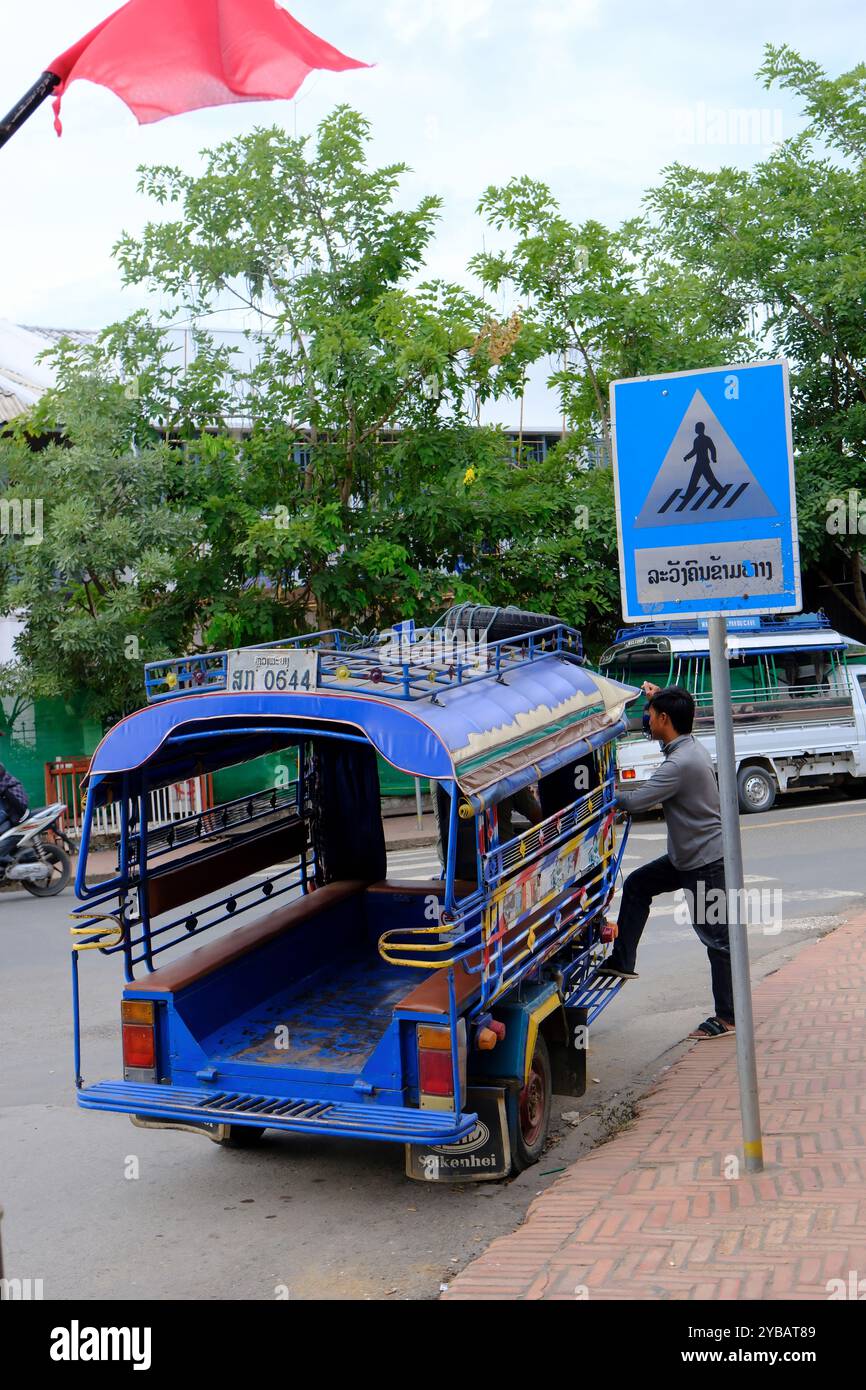 Ein Tuk Tuk wartet auf den Kunden auf der Straße an einem Fußgängerschild. Luang Prabang. Laos Stockfoto