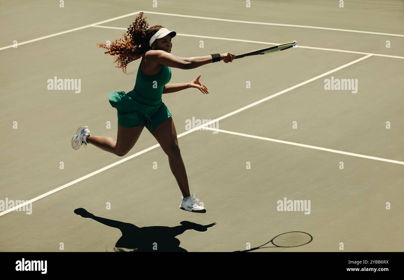 Professionelle Tennisspielerin, die während eines Spiels auf dem Platz einen mächtigen Vorhand-Treffer ausführt und Stärke und Geschick zeigt. Stockfoto