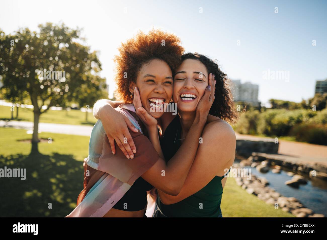 Zwei Freunde, die sich fröhlich in einem sonnigen Park umarmen und die Essenz von Glück, Freundschaft und Verbindung einfangen, die ein Leben lang andauert. Stockfoto