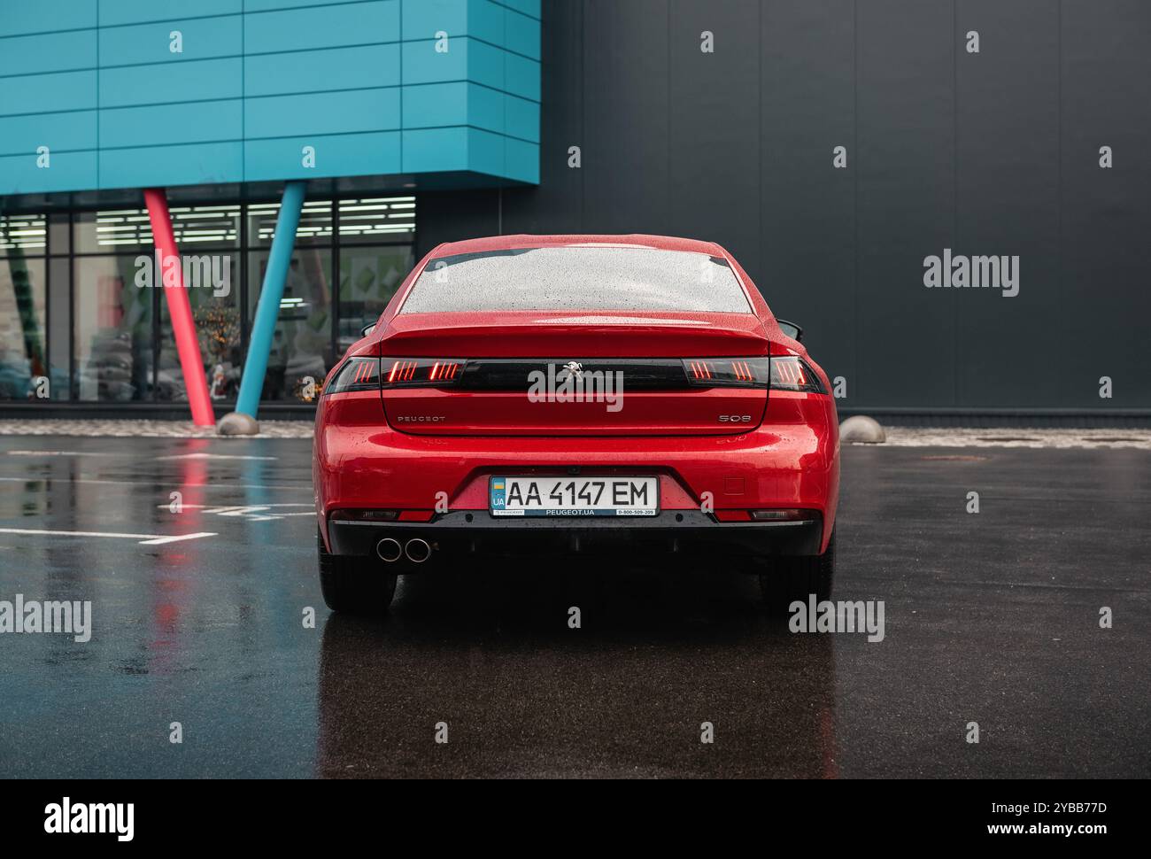 Peugeot 508 an einem regnerischen Tag in einer Stadt. Rückansicht der roten französischen Limousine auf nassem Asphaltparkplatz. Stockfoto