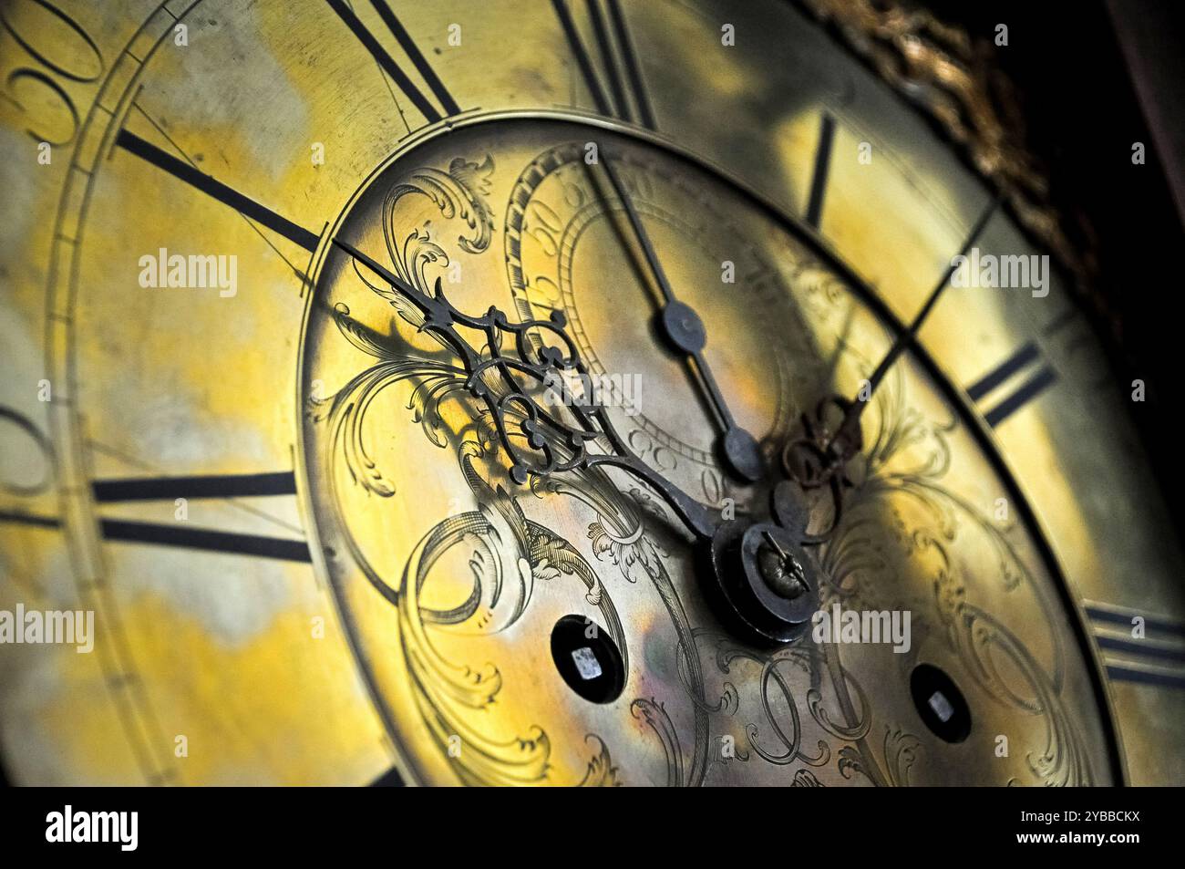 Nahaufnahme der Zeiger, römischer Ziffern und kunstvoller dekorativer Gestaltung einer antiken Uhr. Stockfoto