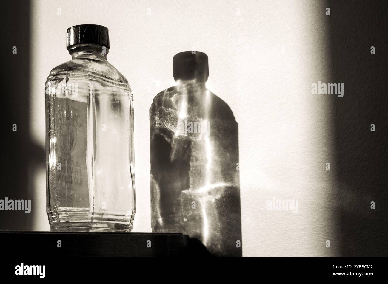 Fotos von Klarglasflaschen und deren Reflexionen und Schatten an der Wand. Stockfoto