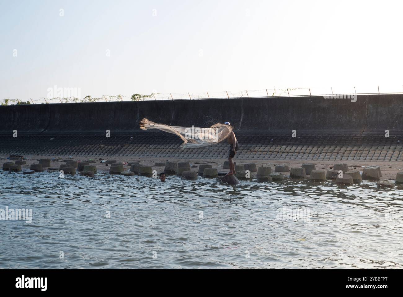 Ein Fischer wirft sein Netz auf den Strand Stockfoto