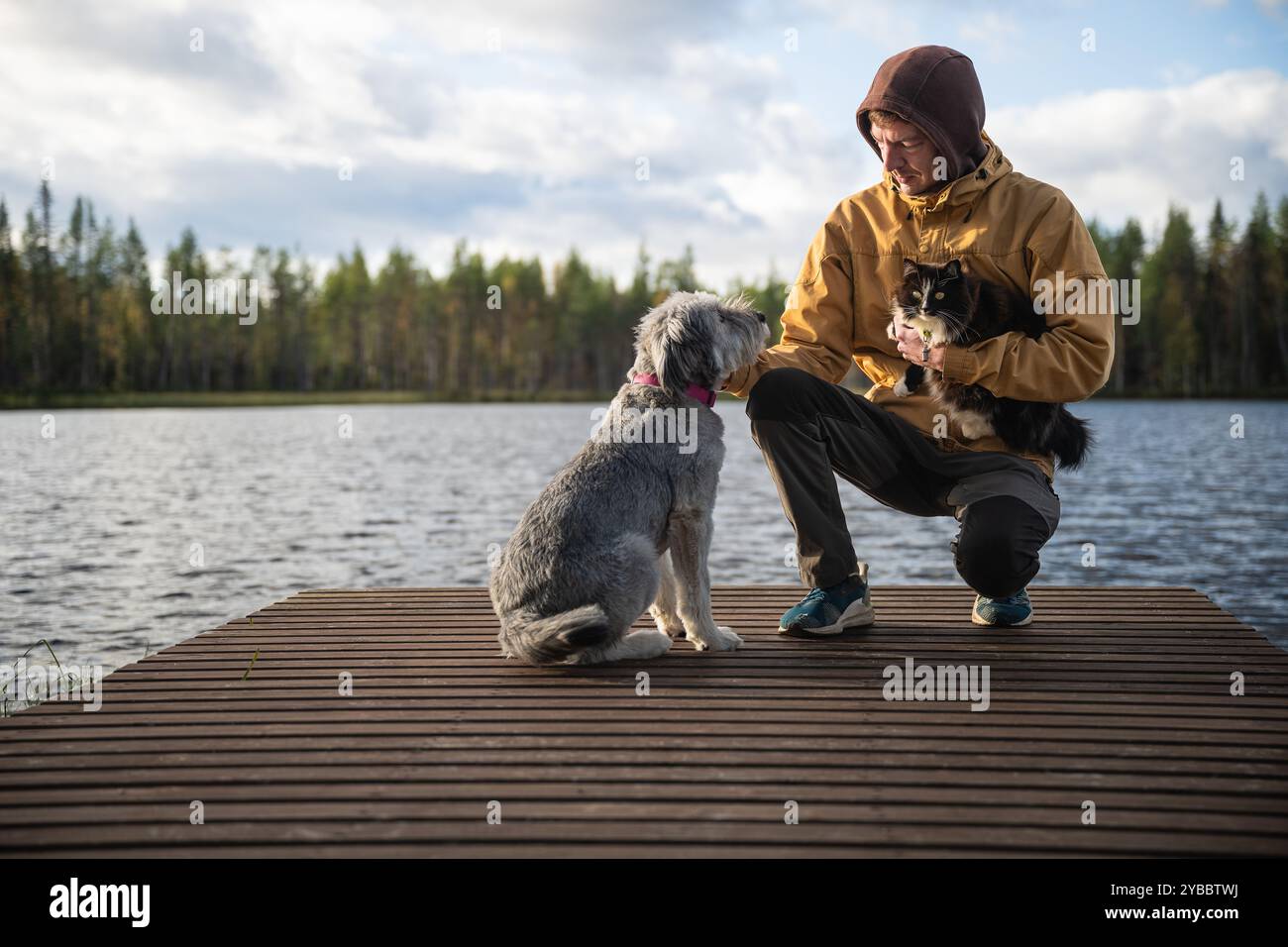 Mann mit Hund und Katze, der auf einem Holzsteg sitzt Stockfoto