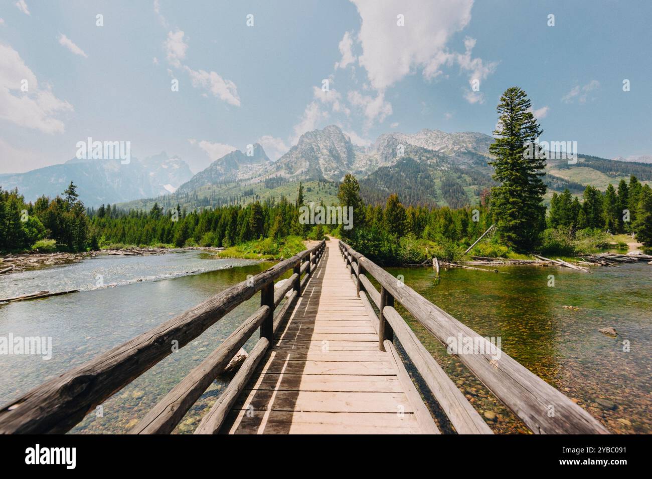 Eine hölzerne Brücke führt zu einem weiten Gebirgszug. Stockfoto