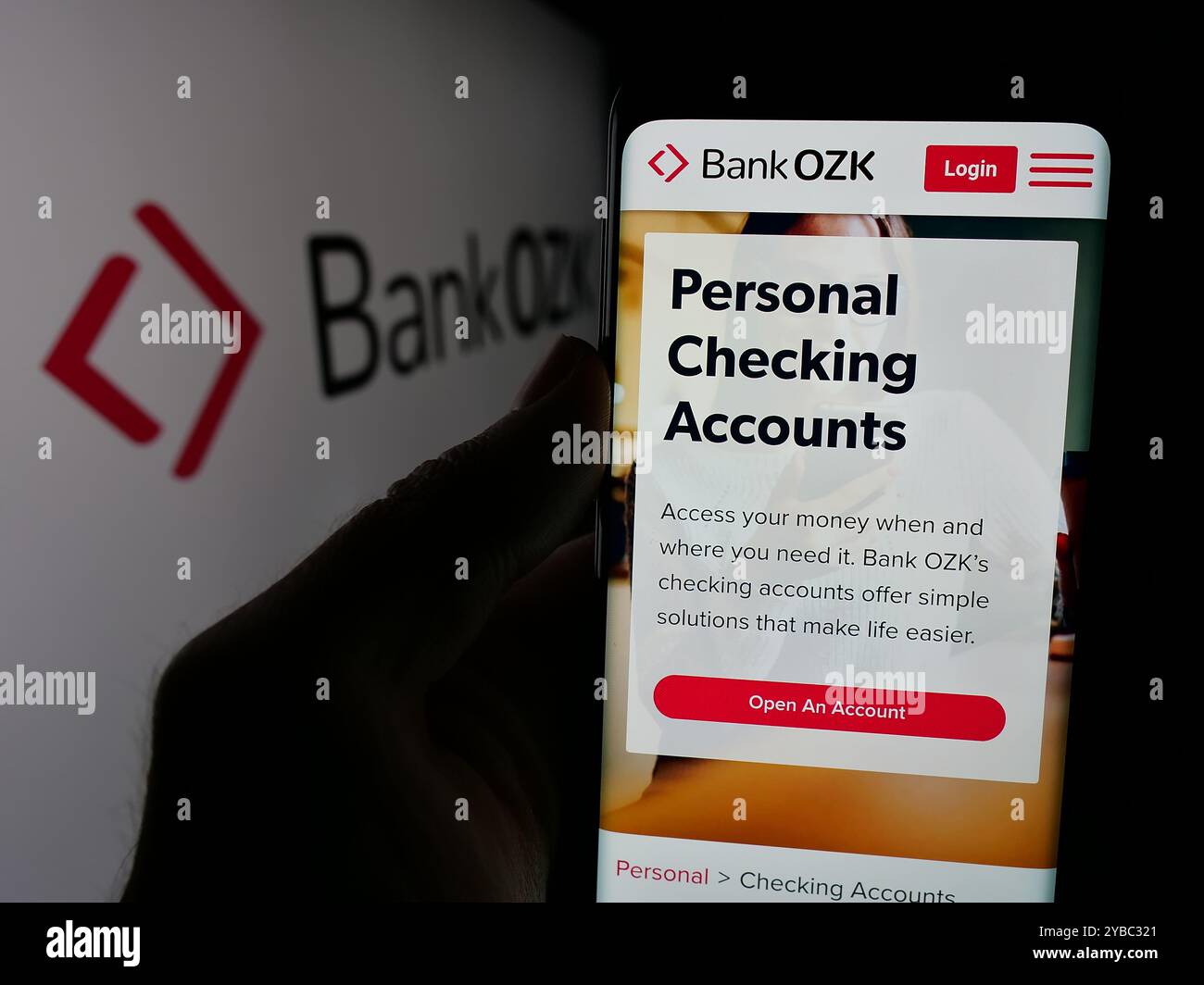Person, die ein Mobiltelefon hält, mit der Webseite des US-Finanzdienstleisters Bank OZK vor dem Logo auf dem Bildschirm angezeigt wird. Konzentrieren Sie sich auf die Mitte des Telefondisplays. Stockfoto