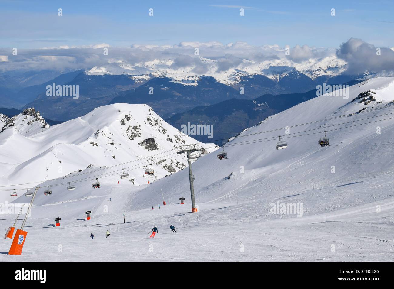 Skifahrer und Snowboarder, die Pisten im Skigebiet Les Menuires absteigen. Wintersportangebote mit Blick auf die schneebedeckten Berge in den drei Tälern. Stockfoto