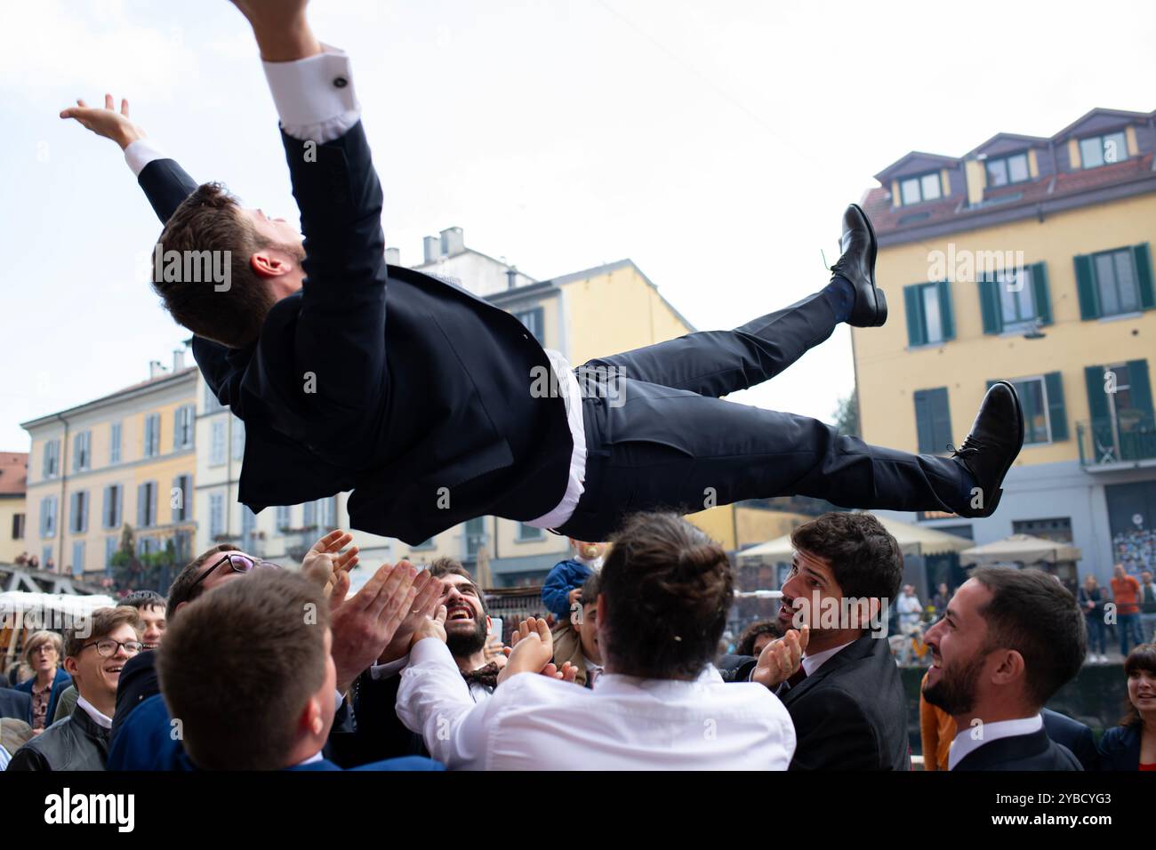 Der italienische Hochzeitsbräutigam wird von Freunden in die Luft geworfen, eine italienische Tradition Stockfoto