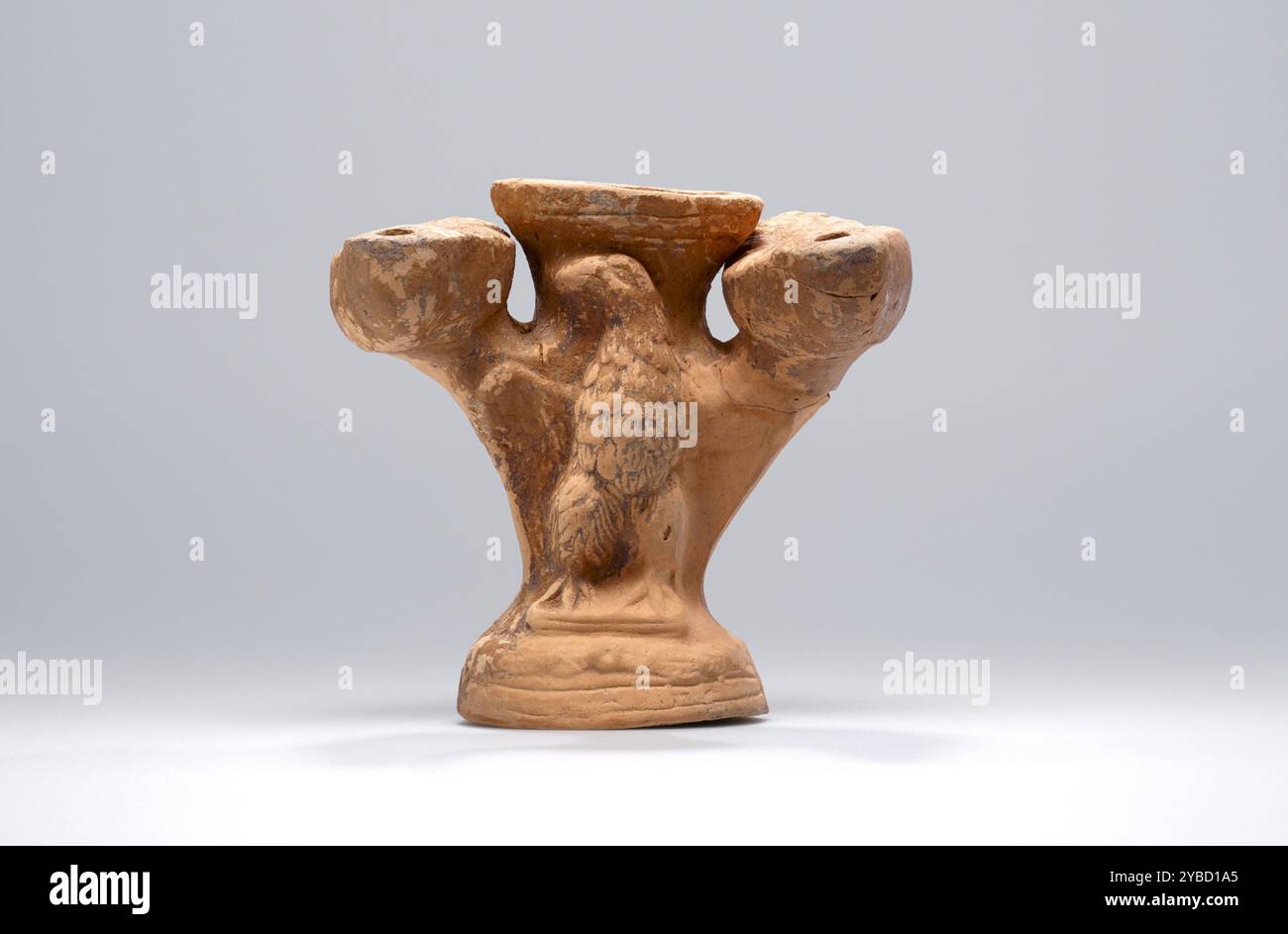 Lampe, Ende des 2. Jahrhunderts n. Chr. zusätzliche Info: Diskus-Ikonographie: Einfacher Diskus. Lampenständer/Räucherbrenner, bestehend aus einem Hohlkörper, der auf einem kreisförmigen Spreizsockel befestigt und von einer Schüssel überlagert ist. Oberteil mit zwei angewendeten Leuchten, eine auf jeder Seite. Vorne in der Mitte befindet sich ein Adler im Hochrelief mit ausladenden Flügeln, Krallenfüße auf einer Plattform, Kopf nach links gedreht, Federn sorgfältig gerendert. Die runde Schüssel kann zum Verbrennen von Weihrauch vorgesehen sein; flacher Rand mit einer tiefen Nut abgegrenzt. Identische Begrenzungsleuchten, jeweils mit einem verlängerten Gehäuse mit einem flachen blattförmigen Verzierungsgriff und einer runden Spitze Stockfoto