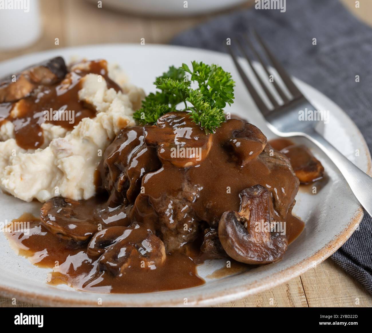 Salisbury-Steak mit Pilzsoße garniert mit Petersilie und Kartoffelpüree auf einem weißen Teller Stockfoto