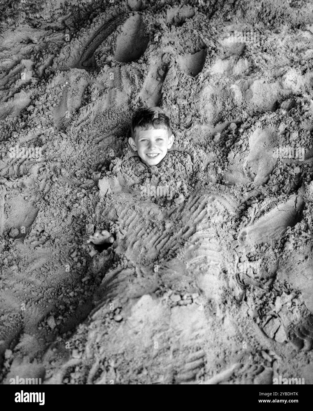 Der siebenjährige Junge spielt im Sand Salcombe Devon, England, Großbritannien Stockfoto