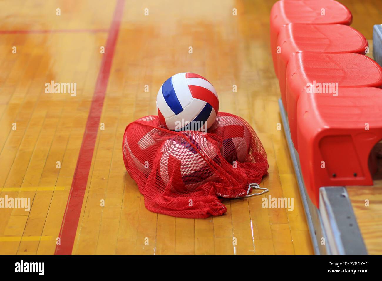 Volleybälle, die nach dem Training in einem roten Netz auf einem Fitnessraum gelagert werden Stockfoto