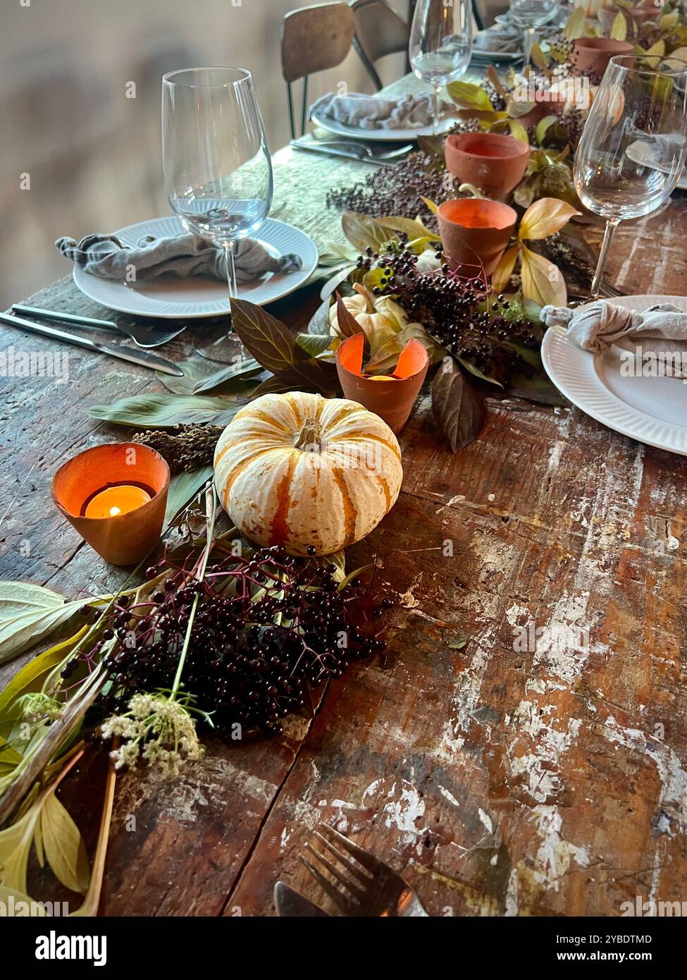 Ein eleganter Herbsttisch mit gestreiftem Kürbis, Kerzen und Beeren schafft eine warme und rustikale Atmosphäre für festliche Zusammenkünfte Stockfoto