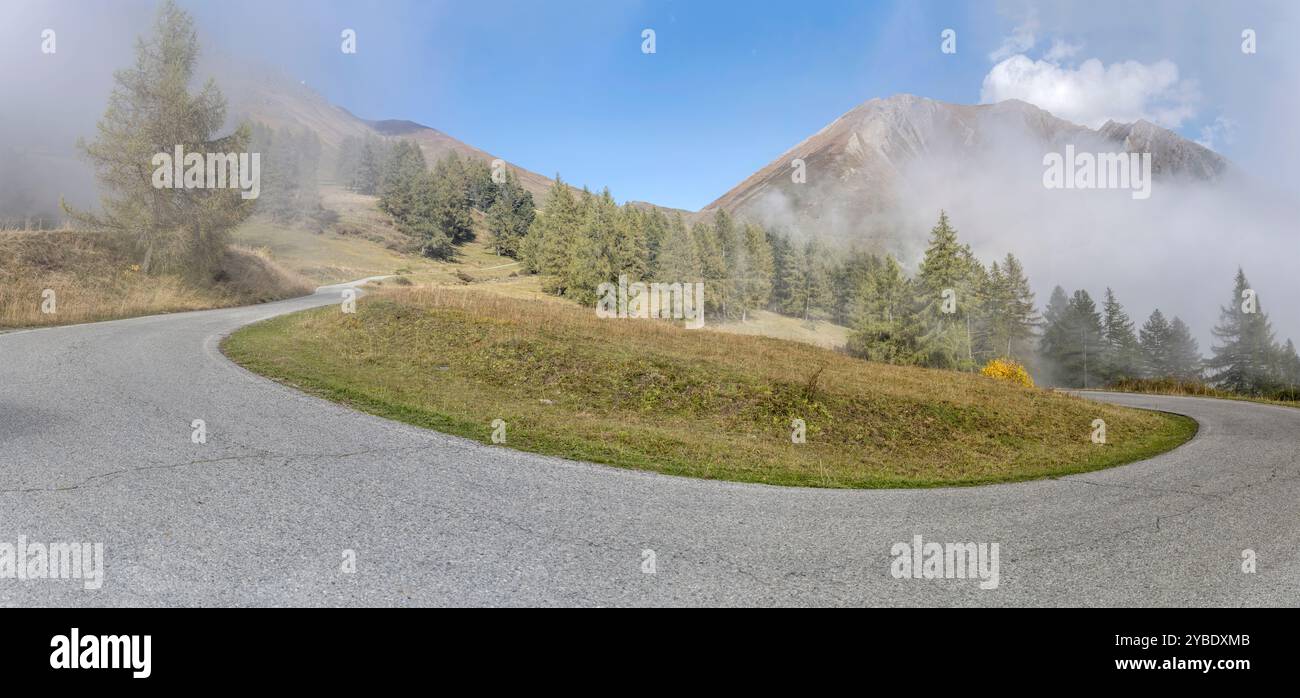 Landschaft mit Straße und Haarnadelkurve im Tannenwald, umgeben von niedrigen Wolken Nebel auf dem Bergland, aufgenommen im hellen Herbstlicht am Pian dell'Alpe, Turin Stockfoto