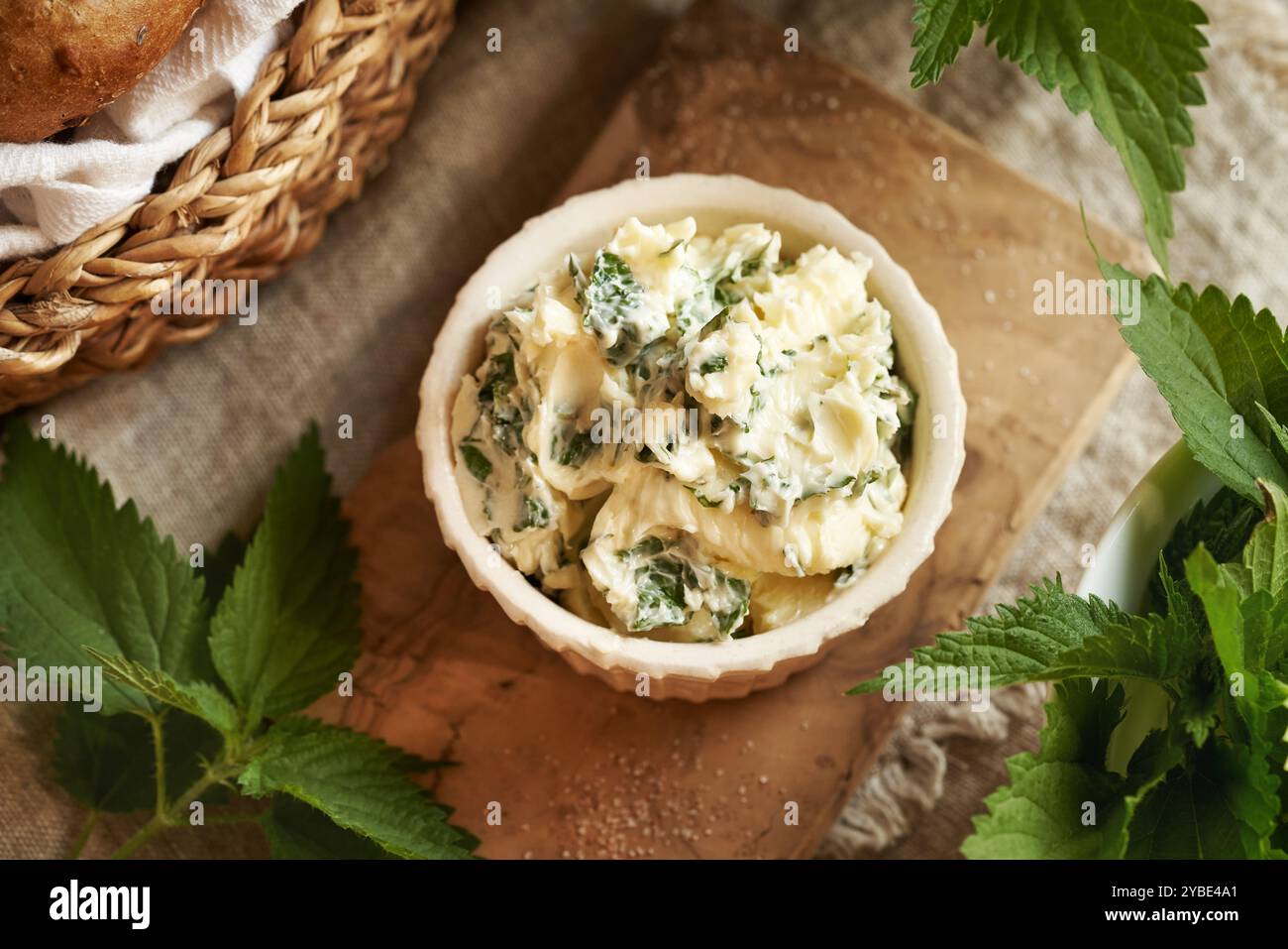 Brennnesselbutter in einer weißen Schüssel auf einem Tisch verteilen Stockfoto