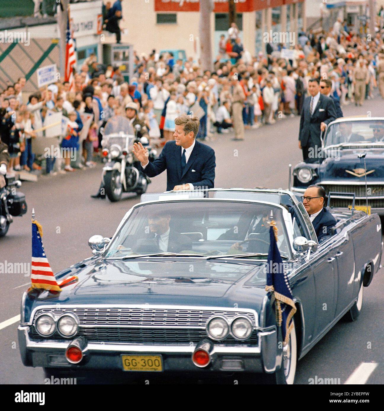 US-Präsident John F. Kennedy (im ersten Auto stehend) mit Gouverneur von Kalifornien, Edmund G. 'Pat' Brown (auf dem Rücksitz), winkend aus dem offenen Cabriolet, Gouverneur von Kalifornien, Edmund G. 'Pat' Brown (auf dem Rücksitz sitzend, während seine Autokasse durch San Diego, Kalifornien, USA, Cecil Stoughton, Fotos des Weißen Hauses, Juni 1963 Stockfoto