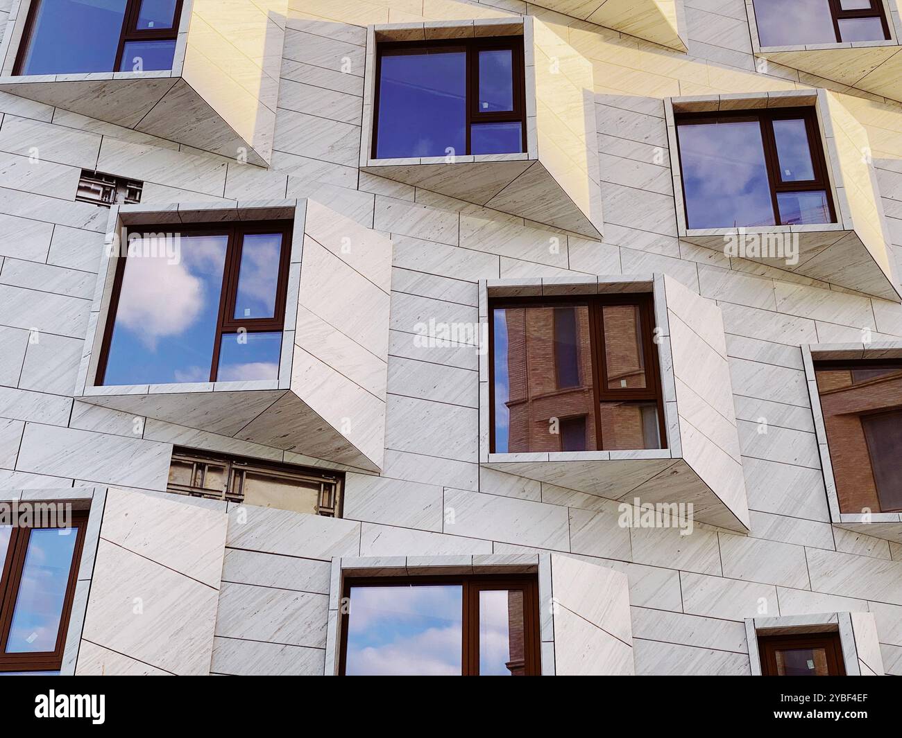 Geometrische Gebäudefassade mit reflektierenden Fenstern und einzigartiger Architektur. Hochwertige Fotos Stockfoto