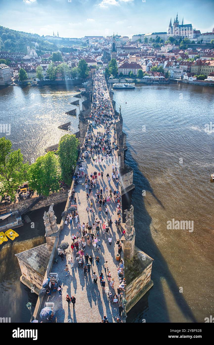 PRAG - 10. MAI 2024: Touristen wandern auf der Karlsbrücke in Prag mit Prager Burg und Moldau im Hintergrund an sonnigen Sommertagen Stockfoto