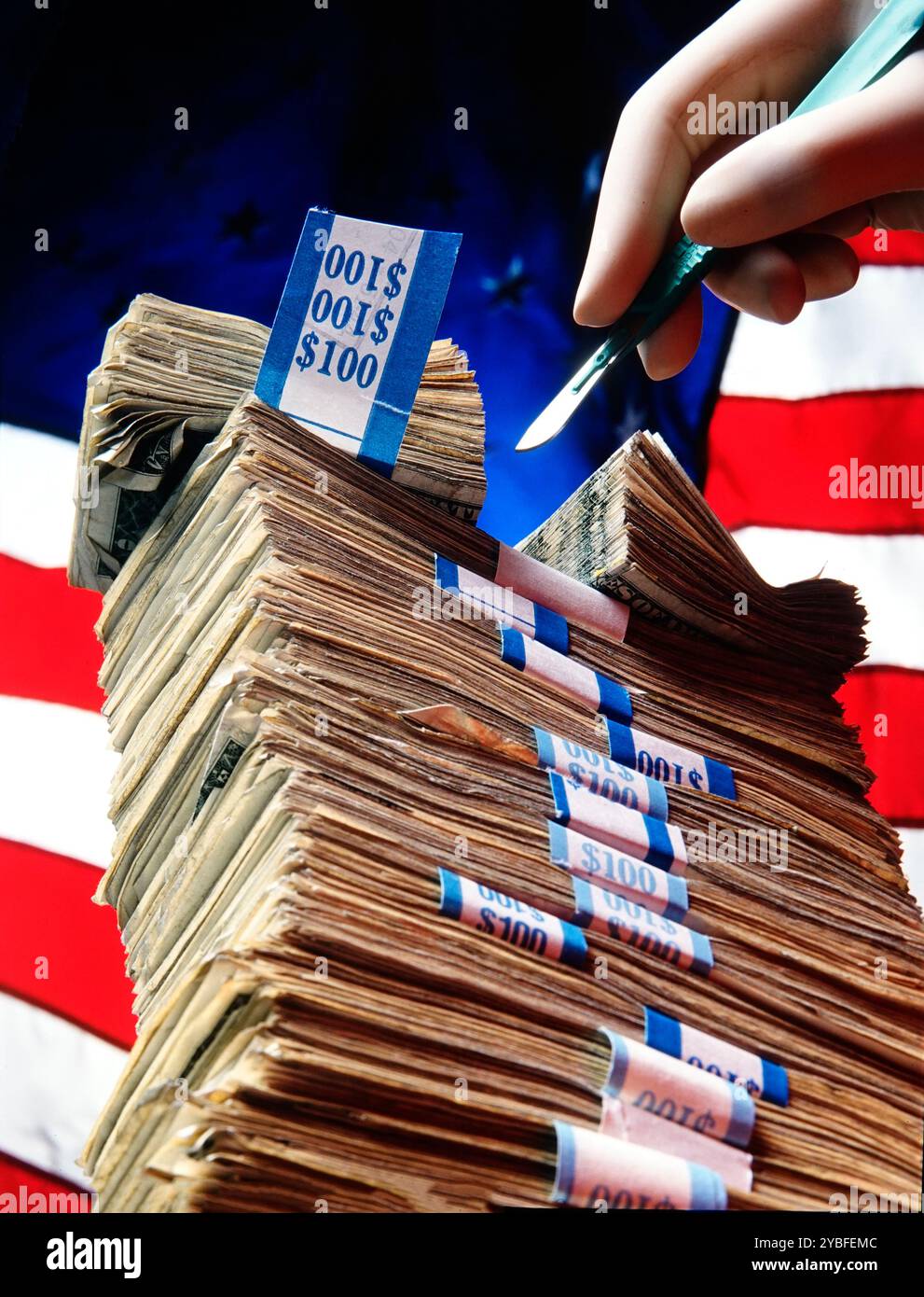 Ein Stapel von hundert Dollar-Scheinen, die Bing chirurgisch in zwei Hälften geschnitten hat, mit amerikanischem Flaggenhintergrund, der Kostensenkungen oder Inflation in Amerika darstellt Stockfoto