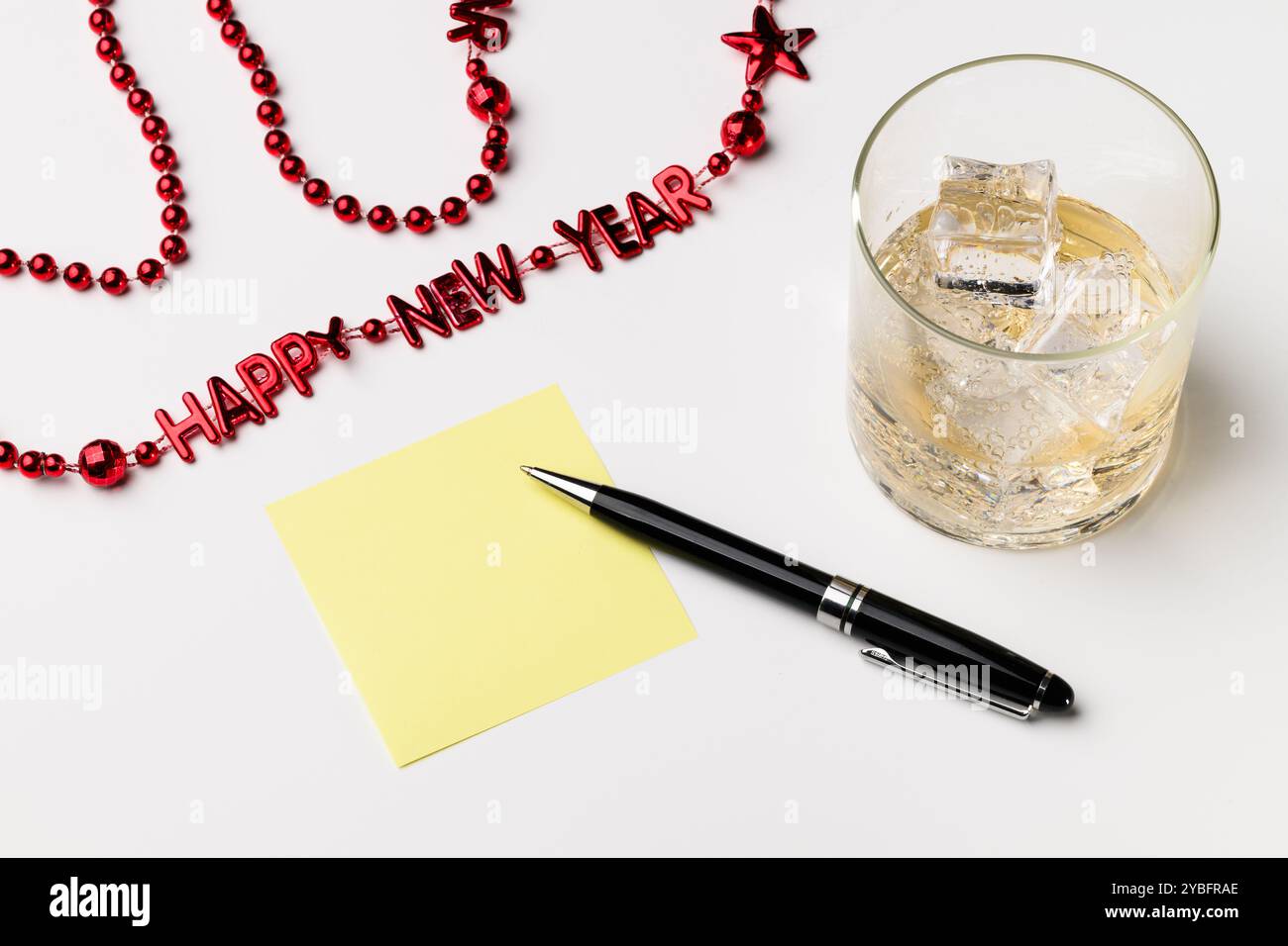 Neujahrsauflösung mit Getränk und rotem Perlenstift und leerem gelben Notizfeld Stockfoto