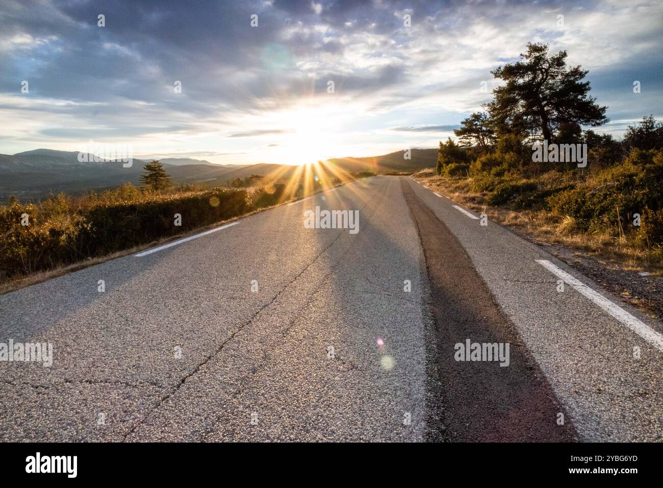 Straße bei Sonnenaufgang mit einer dunkleren Linie von neuem Asphalt, die sich vom benutzten Asphalt abhebt, im Departement Var, Frankreich, Europa. Stockfoto