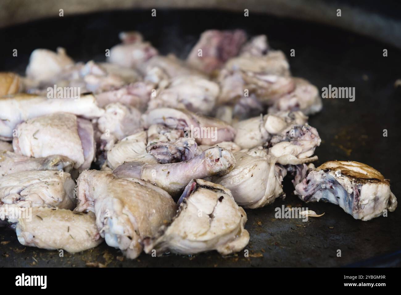 Gebratene Hähnchenschenkel und Flügel. Zubereitung von Hühnerpaella, traditionelles spanisches Essen. Gekocht im Freien bbq Stockfoto