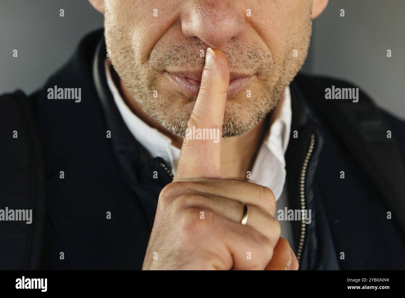 Attraktiv unrasiert erwachsenen Mann mit dem Finger auf die Lippen, stille Geste. Konzept Stockfoto