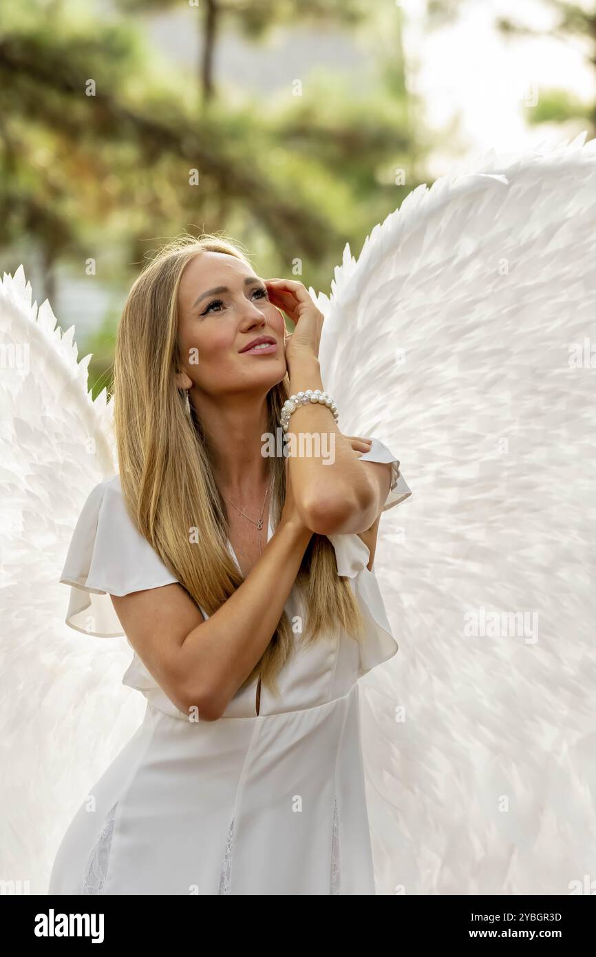 Ein wunderschönes blondes Model posiert im Freien, während es zu halloween weiße Flügel trägt Stockfoto