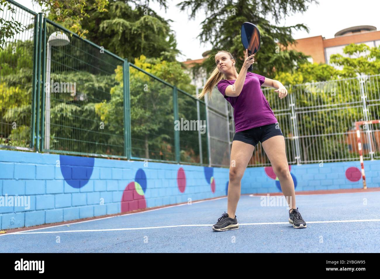 Blonde, energiegeladene und junge Frau, die Pickelball auf einem urbanen Freifeld spielt Stockfoto