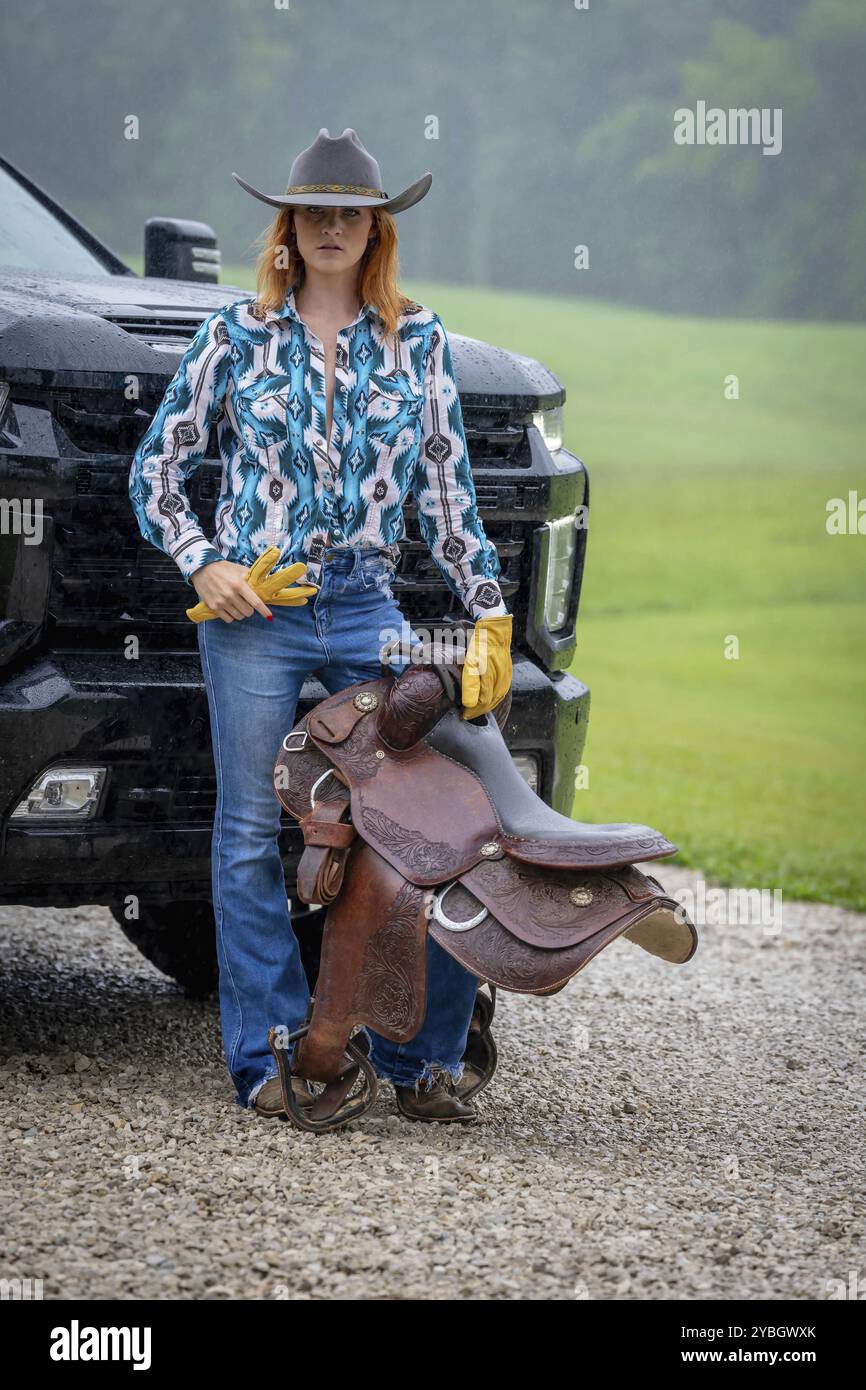 Ein schönes rothaariges Model posiert in einer ländlichen Umgebung in Cowgirl-Kleidung Stockfoto