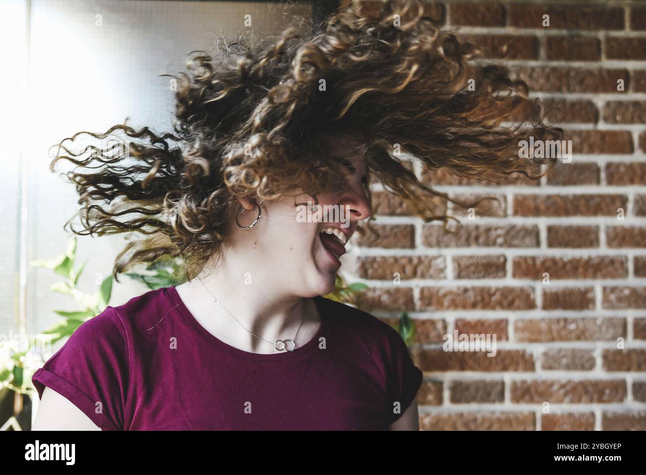 Schöne jugendlich Mädchen schüttelte den Kopf mit dem lockigen Haar auf Stein Hintergrund Stockfoto