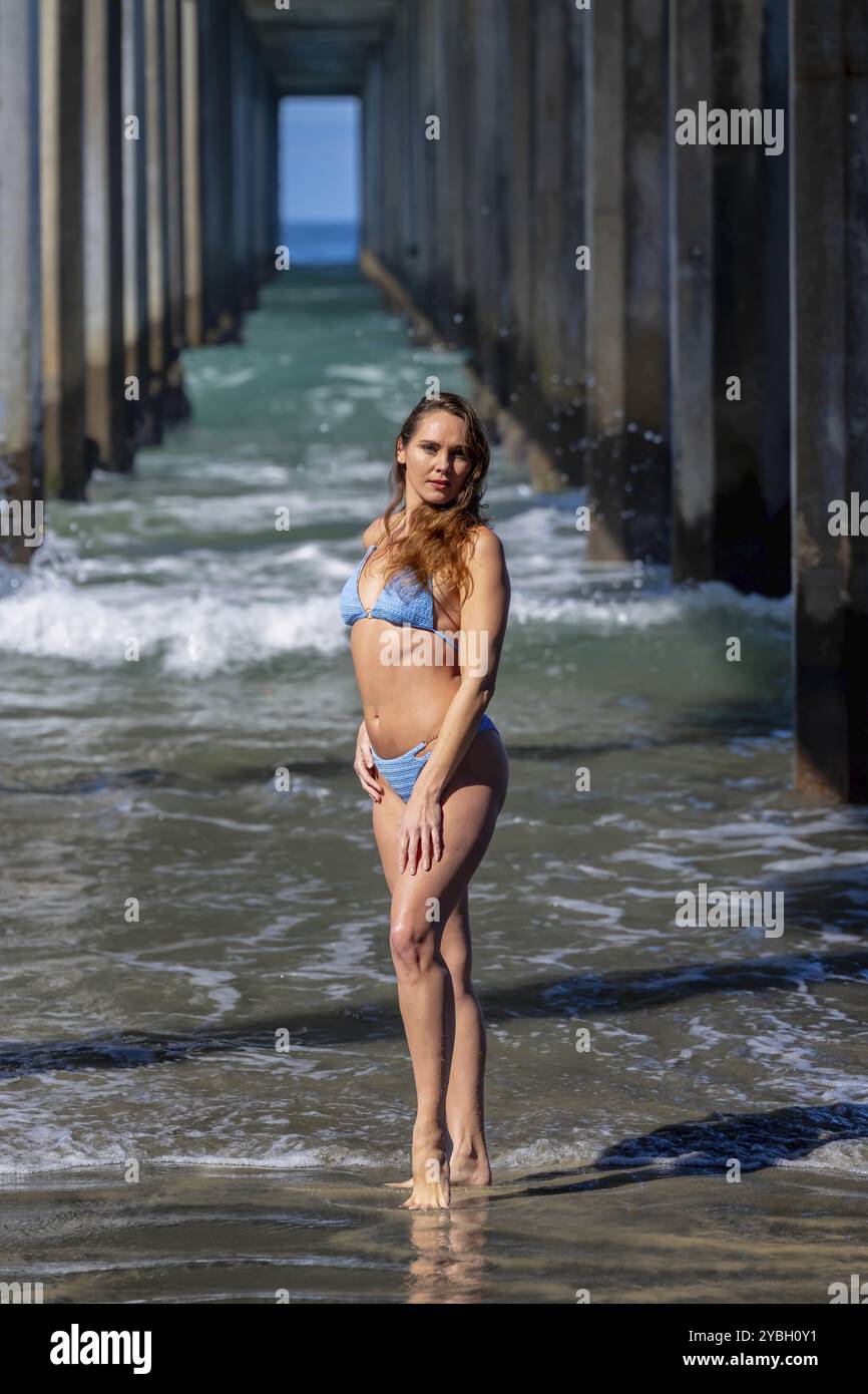 Atemberaubende Frau sonnt sich in der Nähe eines Piers, unter klarem blauem Himmel und genießt die Ruhe eines perfekten Tages am Meer Stockfoto