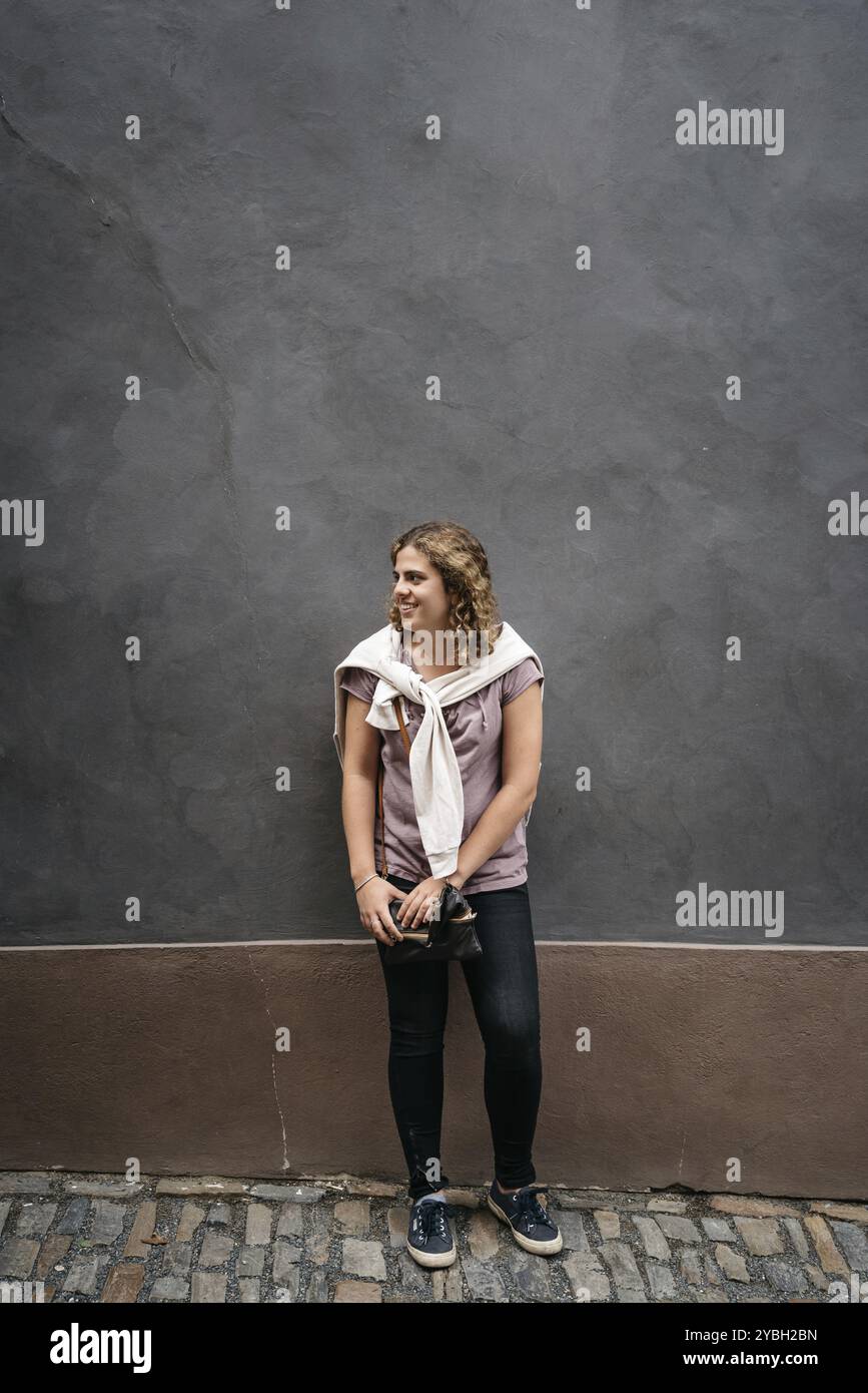 Schöne junge Frau schaut lächelnd gegen die Wand. Konzept Glück und Vertrauen Stockfoto