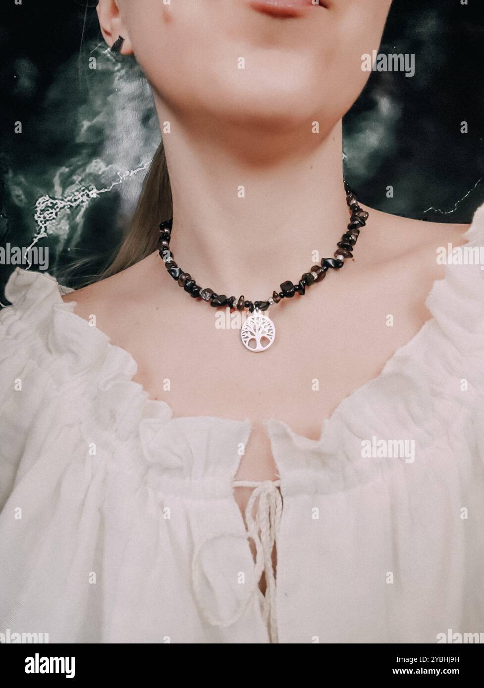 Schwarzer Obsidian-Choker mit Lebensbaum-Anhänger am Hals der Frau Stockfoto