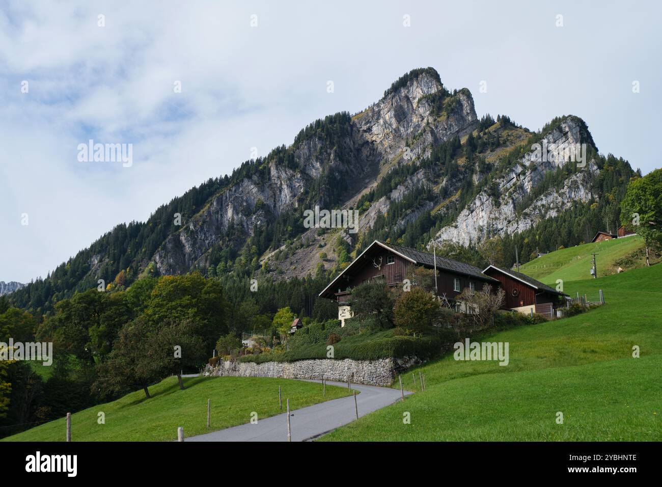 Schweizer Chalet 'Haus FliegenPilz' mit Berggipfel 'Bärensoolspitz' im Hintergrund an einem bewölkten Tag - Teil des Ahornen Rundweges. Stockfoto