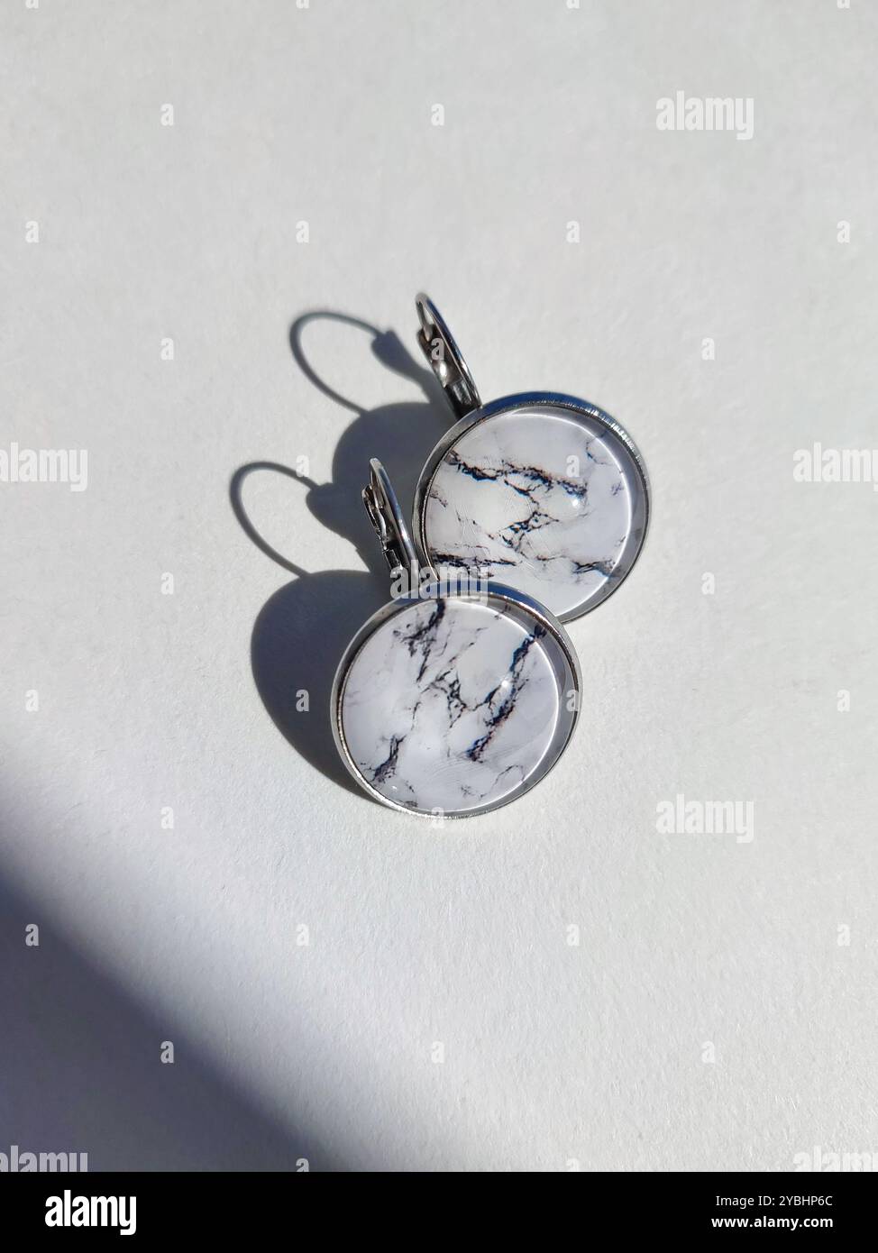 Handgemachte Harz Runde Marmor Textur Stein Ohrringe transparente Oberfläche weißer Schatten Hintergrund. Leverback Haken, sichere Kleidung, naturinspirierter Schmuck Stockfoto