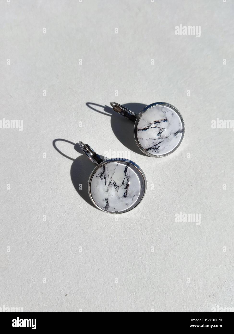Handgemachte Harz Runde Marmor Textur Stein Ohrringe transparente Oberfläche weißer Schatten Hintergrund. Leverback Haken, sichere Kleidung, naturinspirierter Schmuck Stockfoto