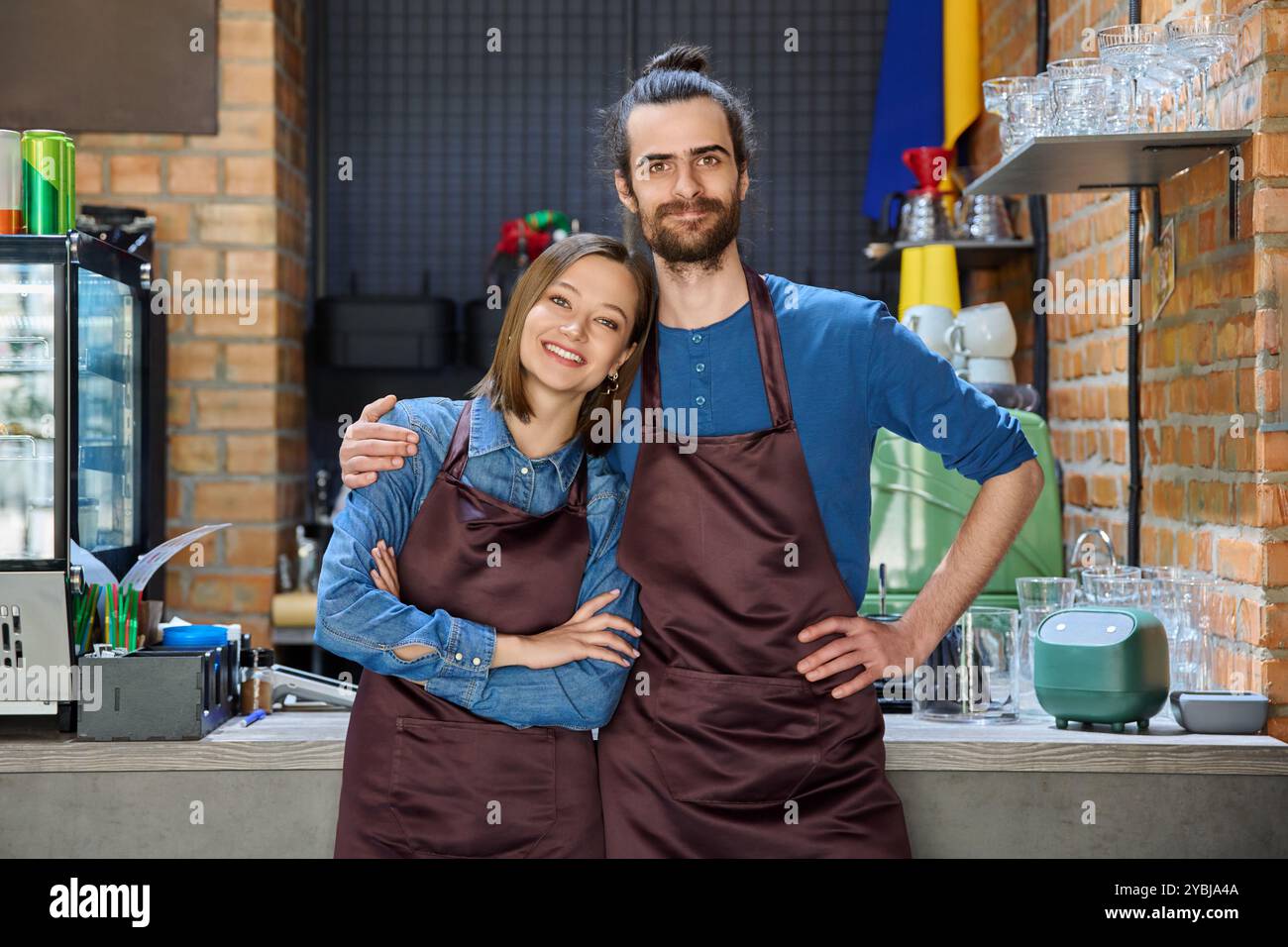 Ein paar Kollegen zu umarmen, Partner junger Mann und Frau in Schürzen am Arbeitsplatz Stockfoto