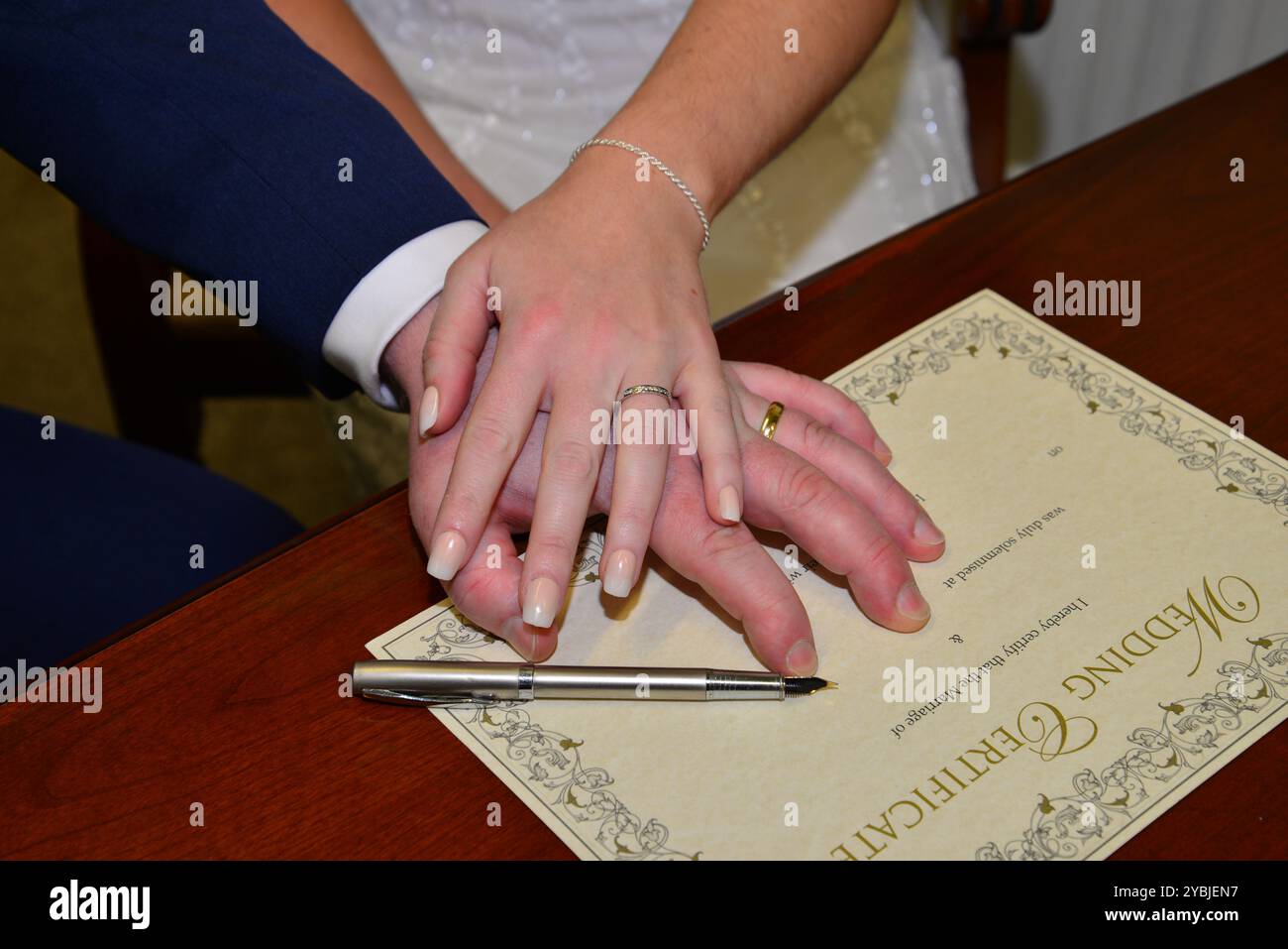 Bild der Braut und des Bräutigams Hände beim Unterschreiben der Hochzeitsurkunde Stockfoto