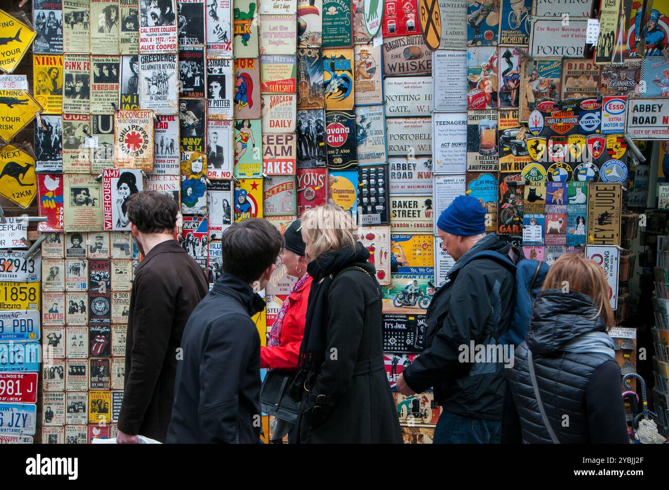 Touristen vor einem Verkaufsstand, an dem auf dem Portobello Road Market Sammlerstücke aus Metall verkauft werden. London Stockfoto