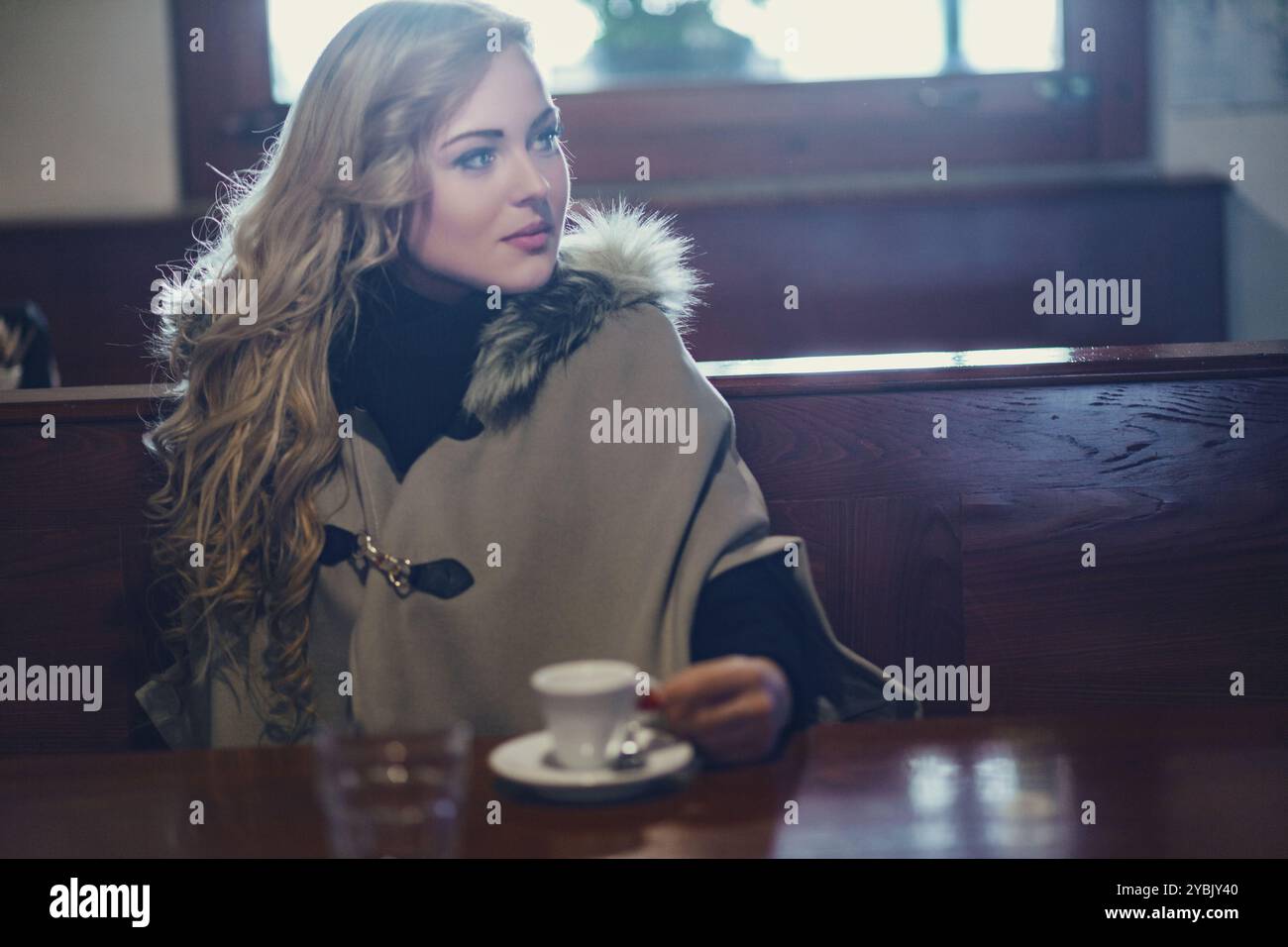 Die junge Frau sitzt in einem Café in italien, genießt eine Tasse Kaffee und genießt die Sehenswürdigkeiten und Geräusche ihrer Umgebung Stockfoto