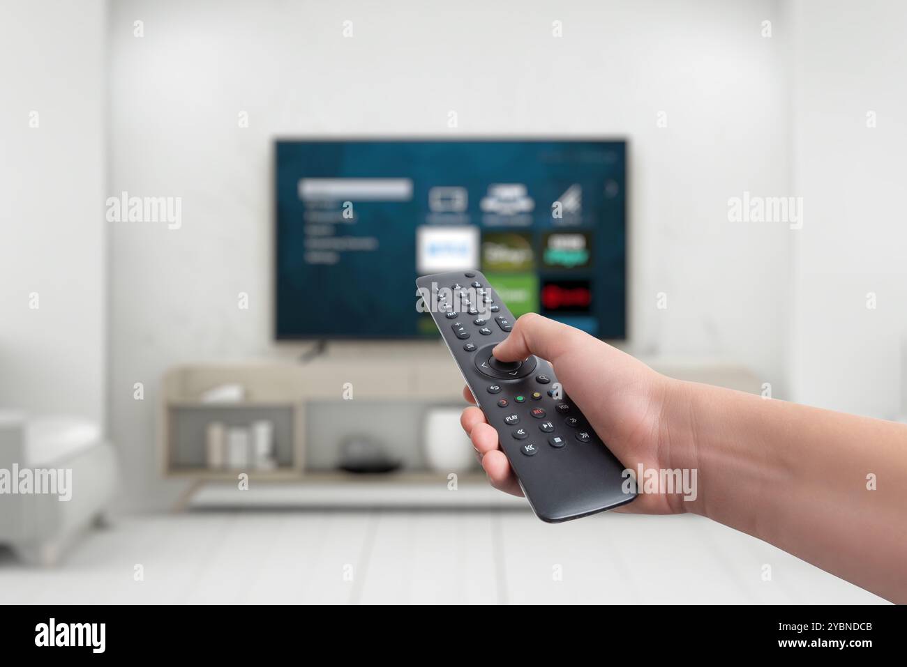 Die Hand hält eine Fernbedienung für einen Smart TV mit App-Tasten für Streaming-Dienste. Konzept der vielseitigen Unterhaltung, die den Funktionsumfang vorstellt Stockfoto