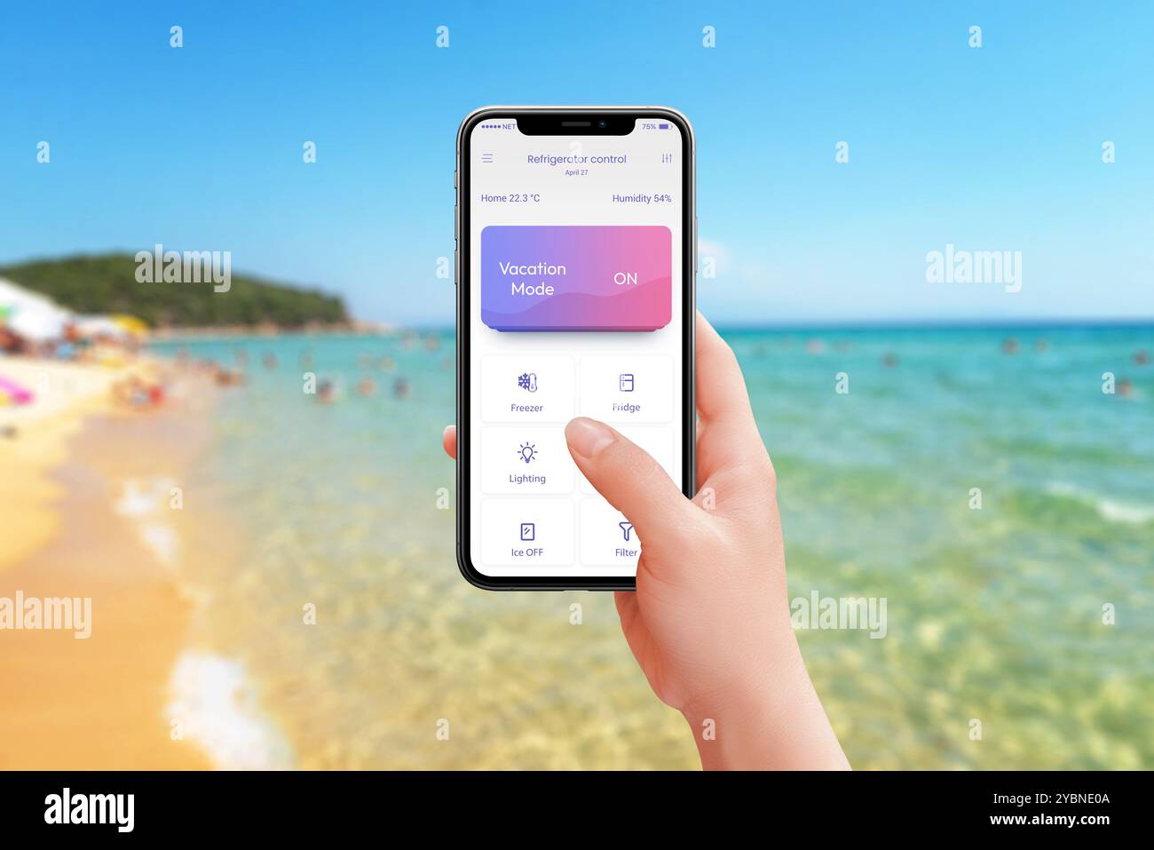 Steuerung von Kühlschrank und Küchengeräten vom Strand aus mit aktiviertem Urlaubsmodus. Mobile App in der Hand, genießen Sie den Komfort Ihres Smart Home und entspannen Sie sich Stockfoto