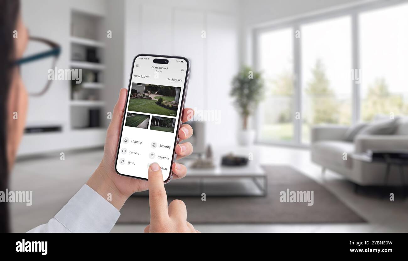 Intelligente Sicherheit für Ihr Zuhause. Eine Frau überwacht Outdoor-Kameras mit ihrem Smartphone und gewährleistet so Sicherheit und Kontrolle über ihre Wohnumgebung von überall aus Stockfoto