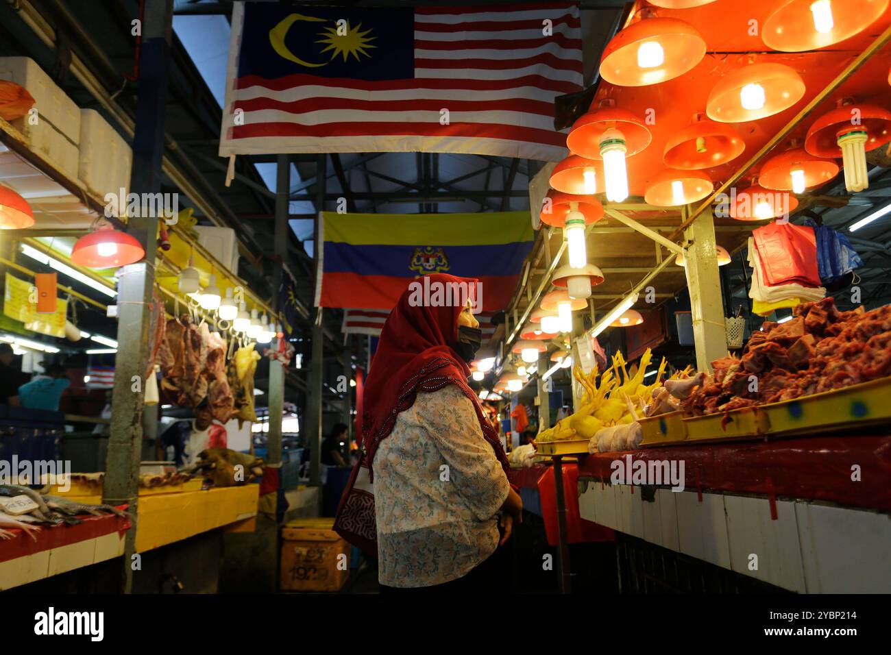 Kuala Lumpur, Malaysia - 3. August 2023: Eine muslimische Frau, die eine Gesichtsmaske trägt, kauft im Frischfleisch-Bereich des Chow Kit Market ein. Stockfoto