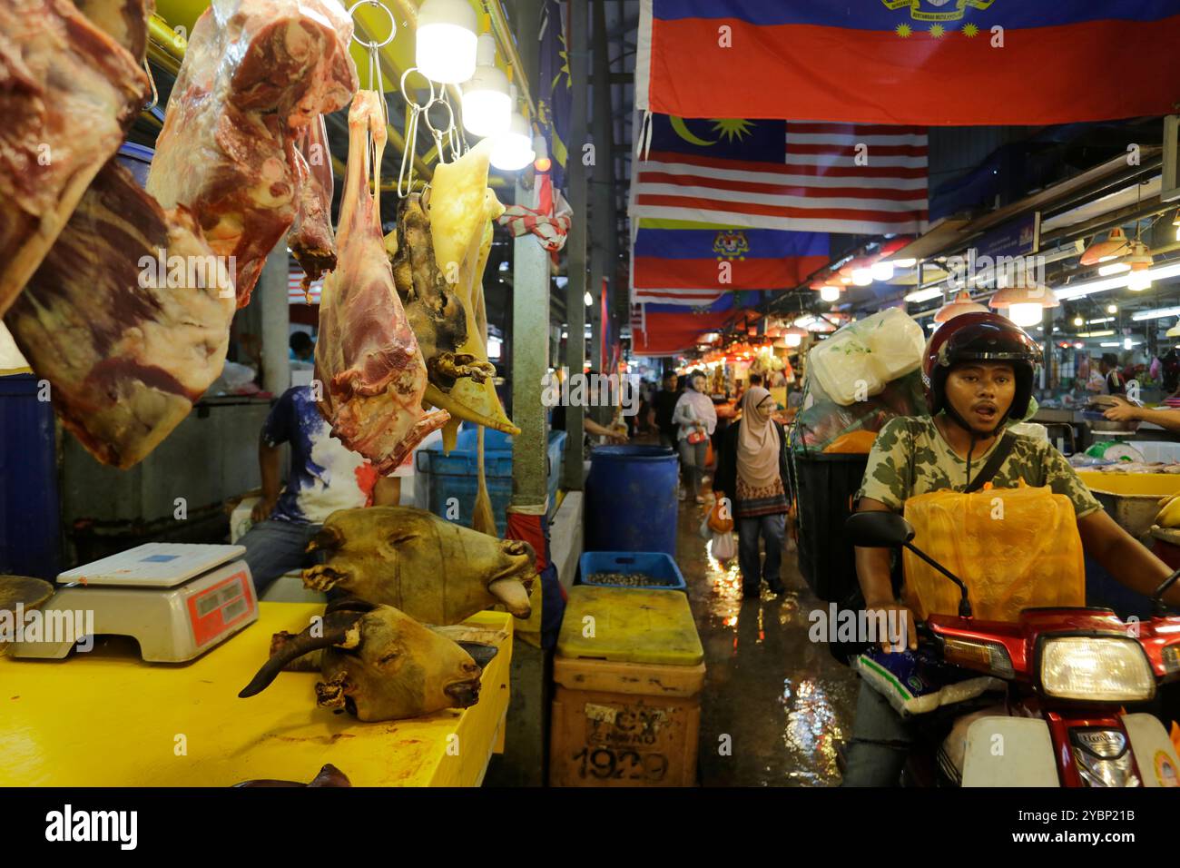 Kuala Lumpur, Malaysia – 3. August 2023: Ein Mann fährt mit seinem Roller durch die Frischfleisch-Sektion des Chow Kit Market. Stockfoto