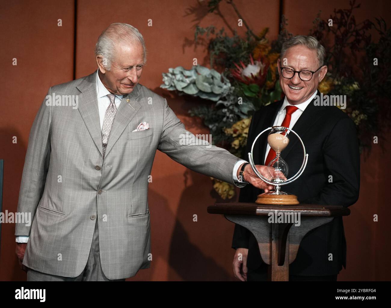 Der Präsident des Legislative Council, Ben Franklin (rechts), sieht zu, wie König Karl III. Eine Sanduhr dreht, die er als Geschenk zur Feier des 200-jährigen Bestehens des Legislative Council in New South Wales überreicht, während einer Veranstaltung zum Jahrestag des New South Wales Parliament House in Sydney am ersten Tag seines Besuchs in Australien und Samoa. Die eigens in Auftrag gegebene Sanduhr wurde im Goldsmith's Centre handgefertigt, wobei die Holzbasis von der King's Foundation aus einer Zedernholzpflanze in seiner Residenz in Highgrove in Großbritannien geliefert wurde. Bilddatum: Sonntag, 20. Oktober 2024. Stockfoto