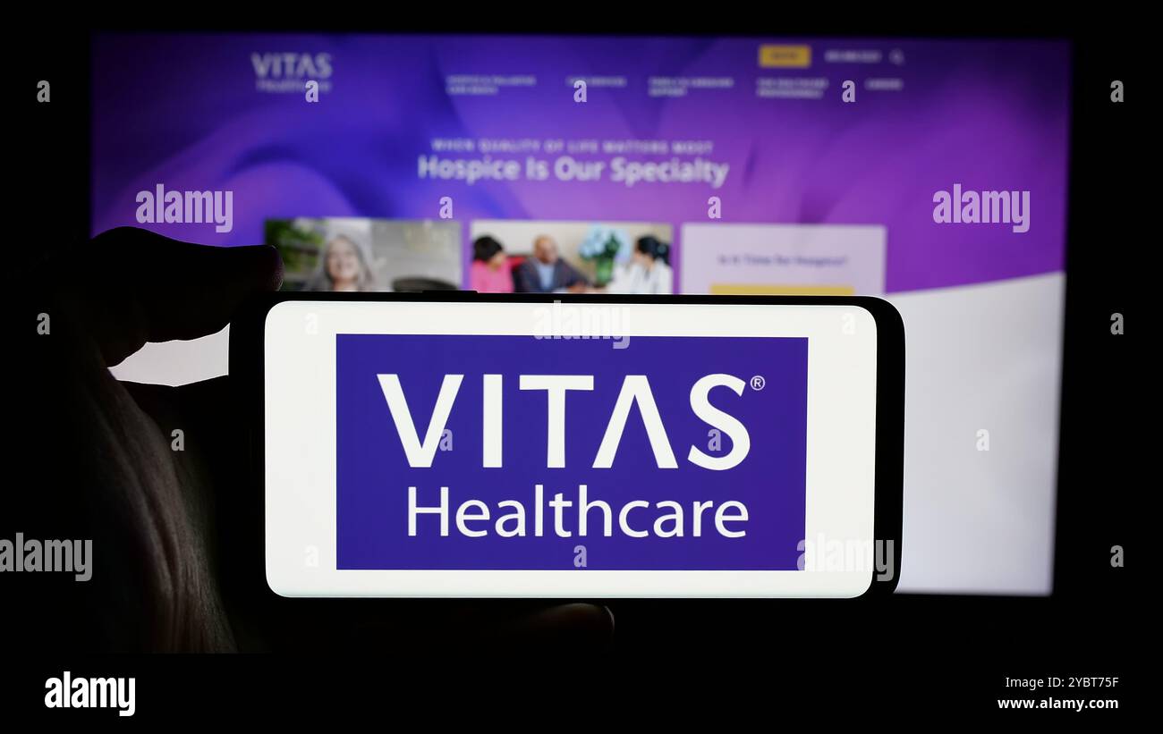 Person, die ein Mobiltelefon mit dem Logo des US-Gesundheitsunternehmens VITAS Healthcare auf dem Bildschirm vor der Business-Webseite hält. Schwerpunkt auf dem Display des Telefons. Stockfoto